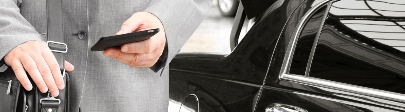 Man checking phone in front of black car